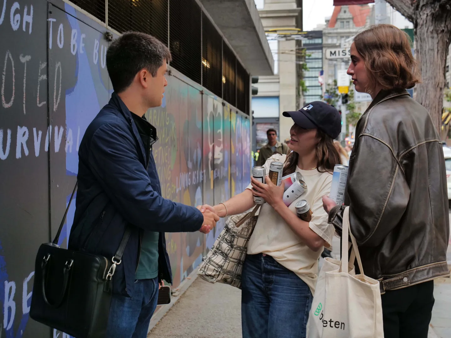 A handshake on a city sidewalk during the can handout